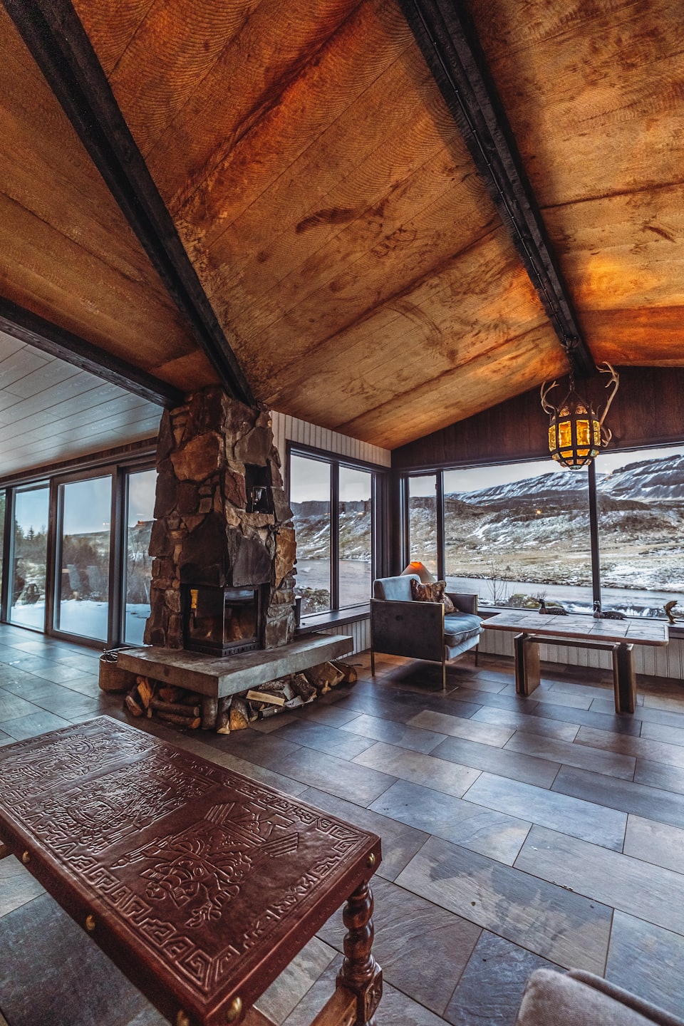 Stone fireplace and large windows overlooking a snow-dusted landscape.