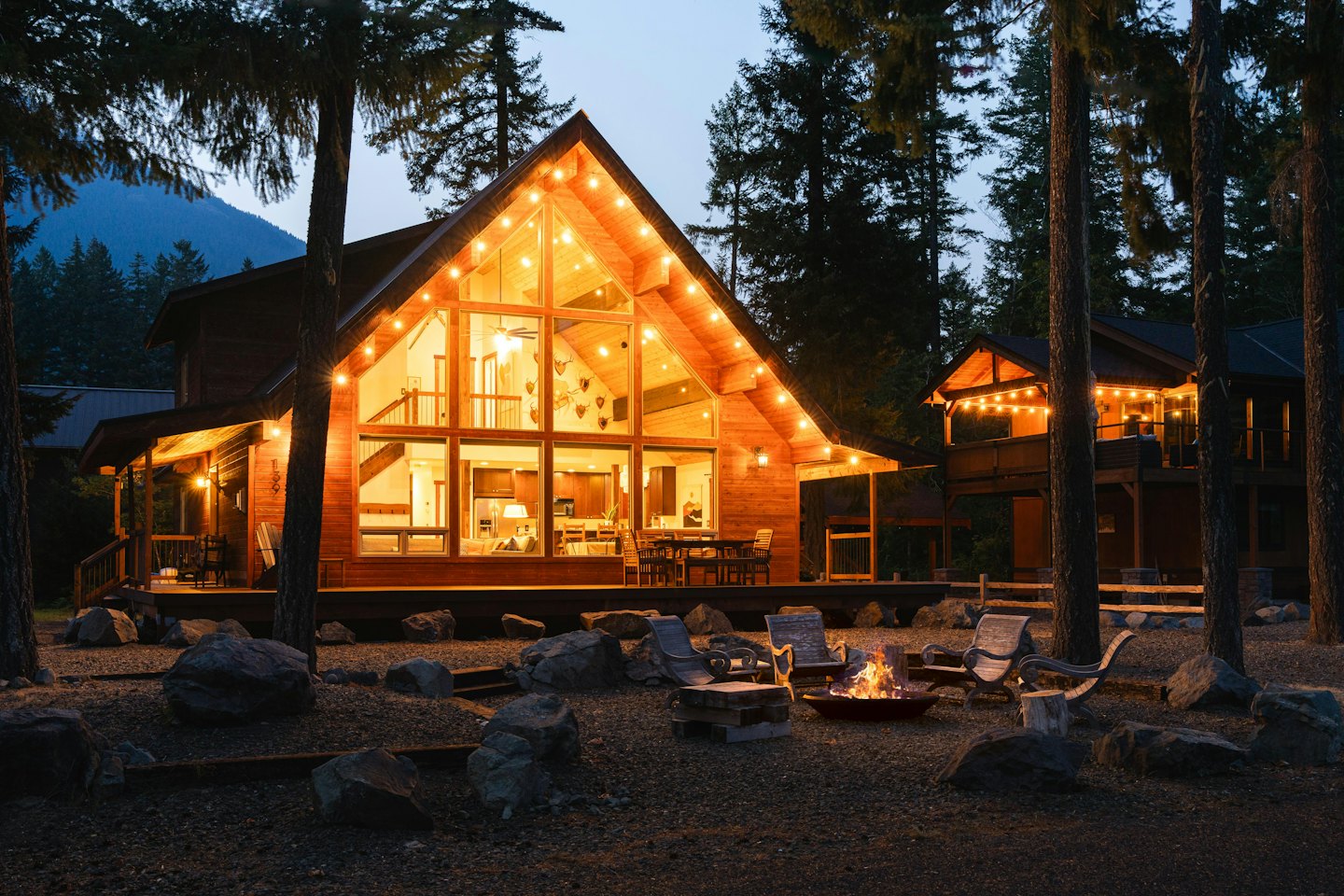 Rustic wooden lodge and cabins nestled among pine trees at dusk.