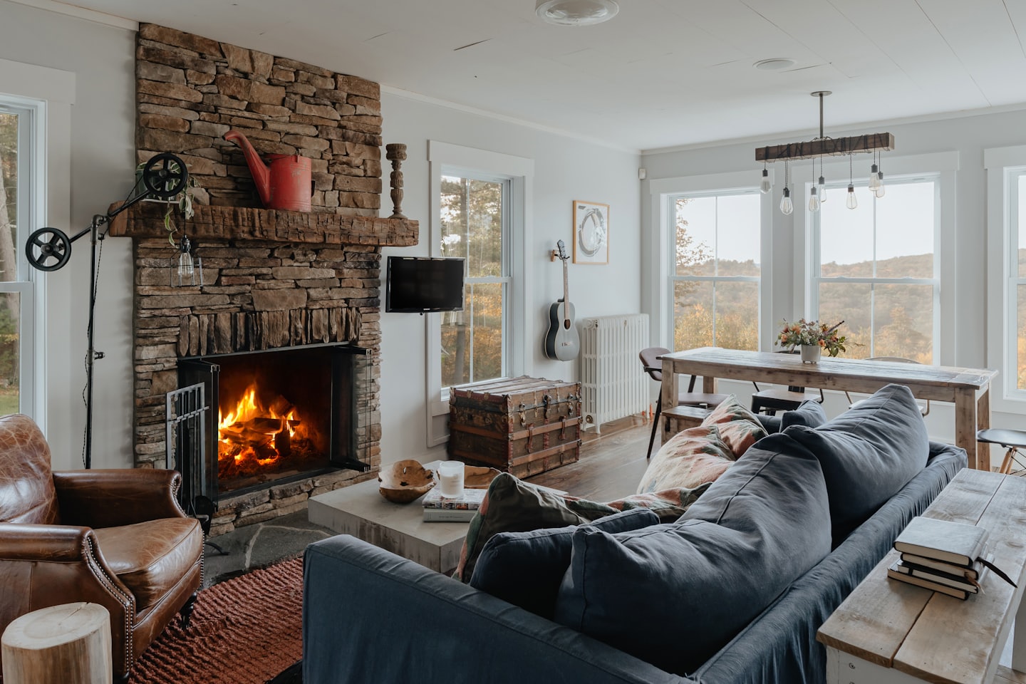 Cozy living room with stone fireplace and autumn view.